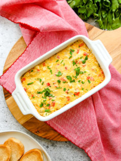 an overhead shot of the roasted red pepper artichoke dip on a red napkin on a round cutting board