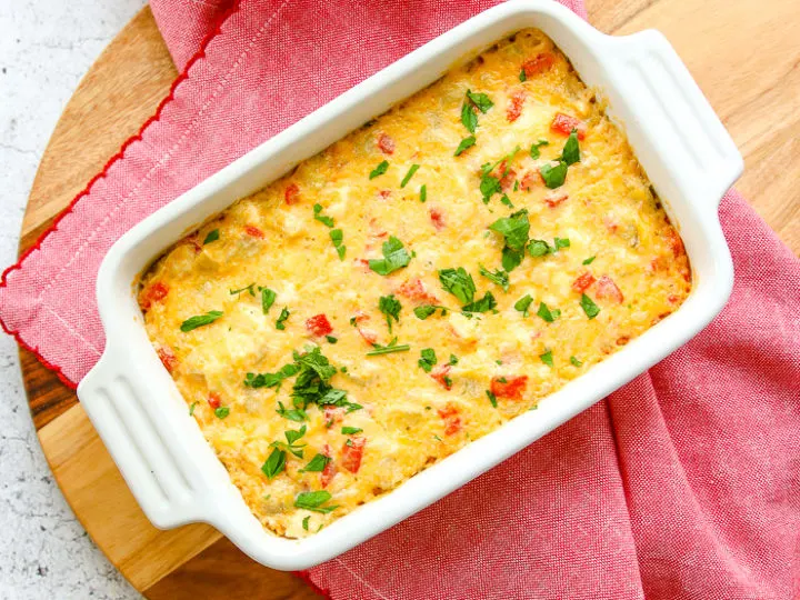 an overhead shot of the roasted red pepper artichoke dip on a red napkin on a round cutting board