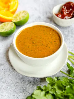 a bowl of chipotle lime sauce on a plate with ingredients around it