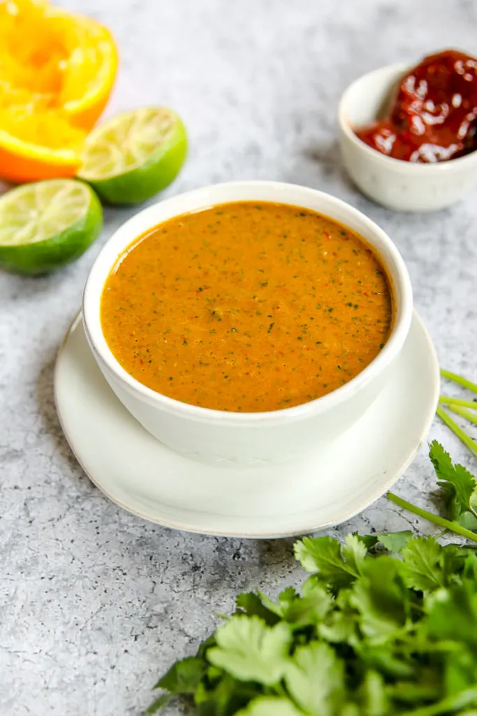 a bowl of chipotle lime sauce on a plate with ingredients around it