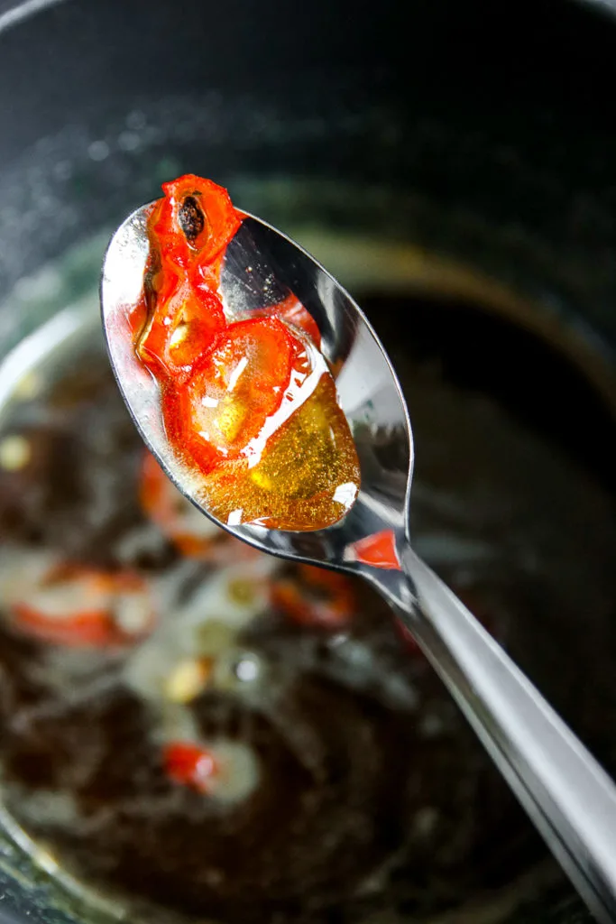 a spoon holding honey and sliced peppers