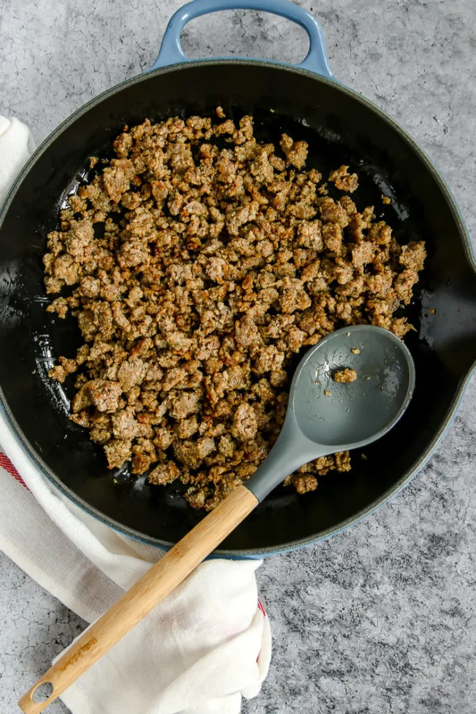 a cast iron pan with cooked, crumbled sausage