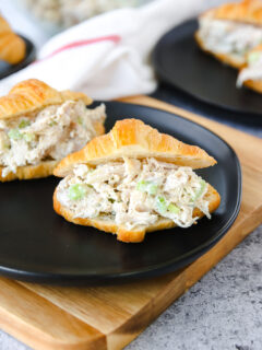 a small croissant with rotisserie chicken salad on a black plate