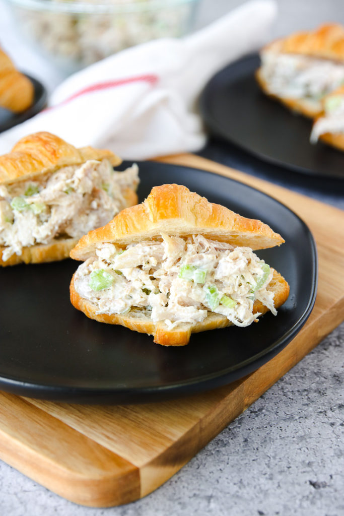 a small croissant with rotisserie chicken salad on a black plate