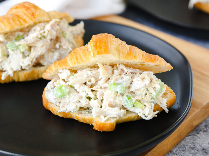 a small croissant with rotisserie chicken salad on a black plate