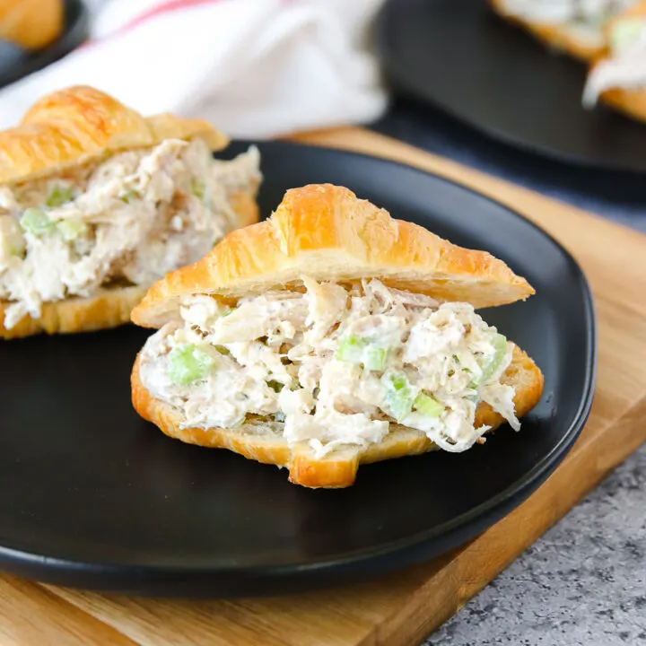 a small croissant with rotisserie chicken salad on a black plate