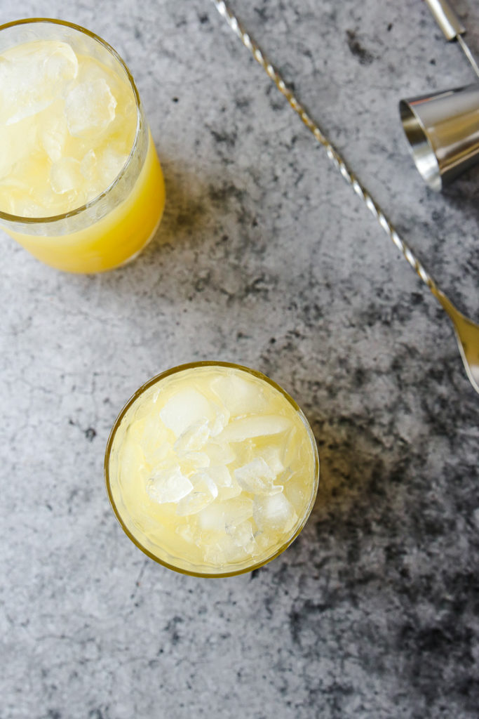 an overhead shot looking down at crushed ice in glasses next to a stirrer