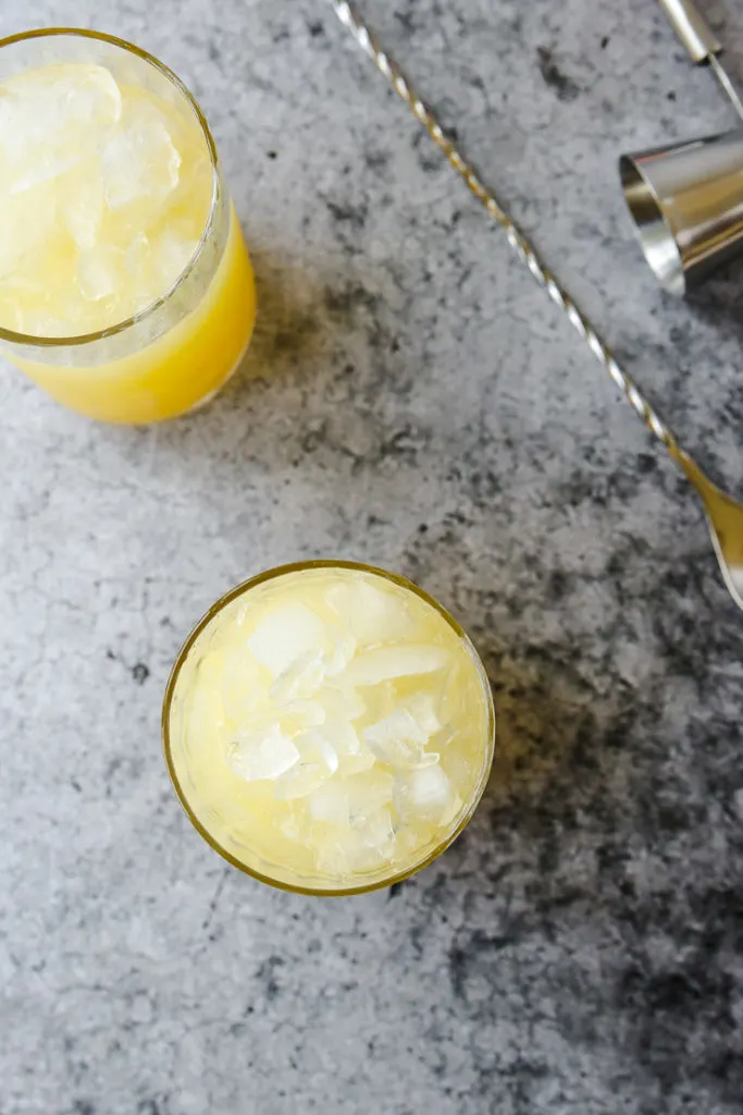 an overhead shot looking down at crushed ice in glasses next to a stirrer