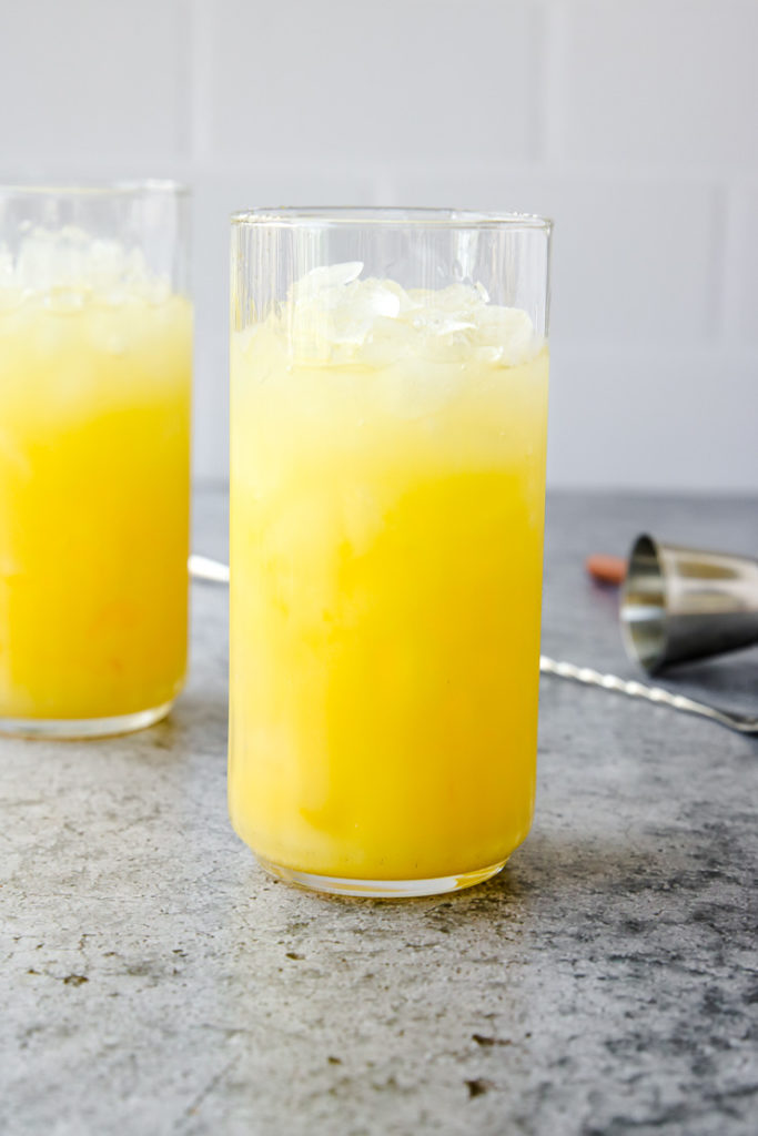 a highball glass full of crushed ice and a screwdriver