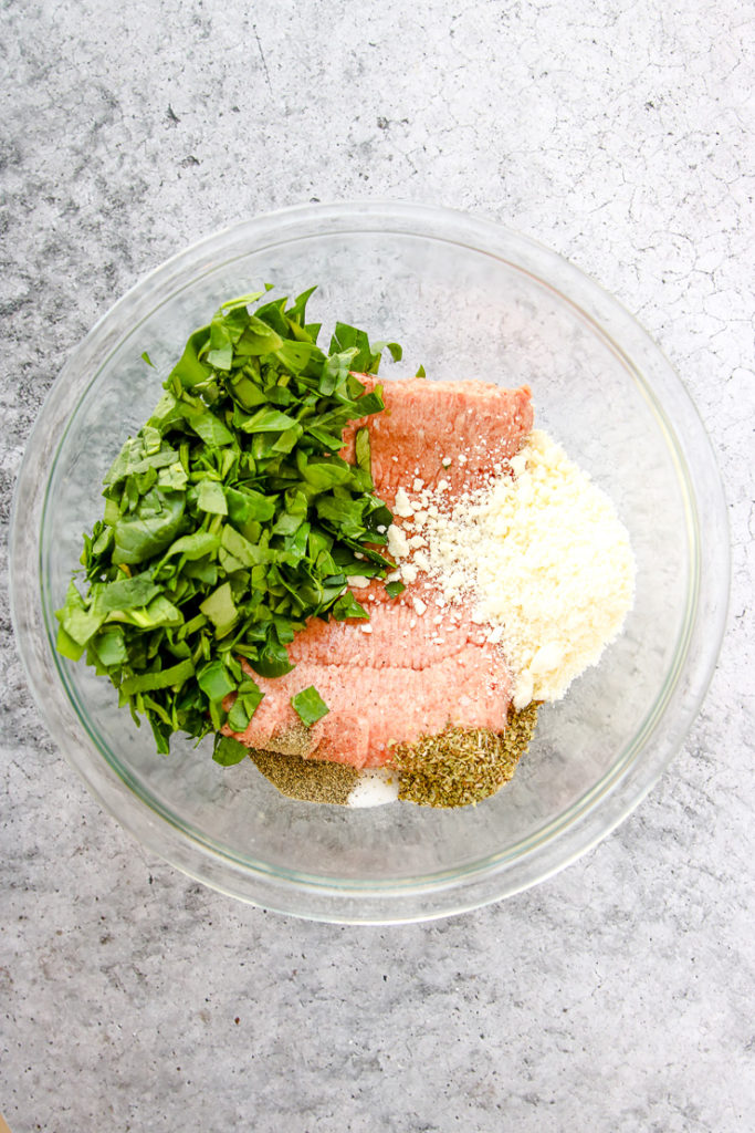 a glass bowl of ground turkey, spinach, feta, and seasonings