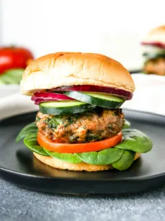 layers of spinach, tomato, a spinach feta turkey burger, cucumber, and red onion on the bun