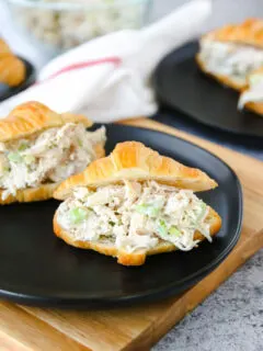 a small croissant with rotisserie chicken salad on a black plate