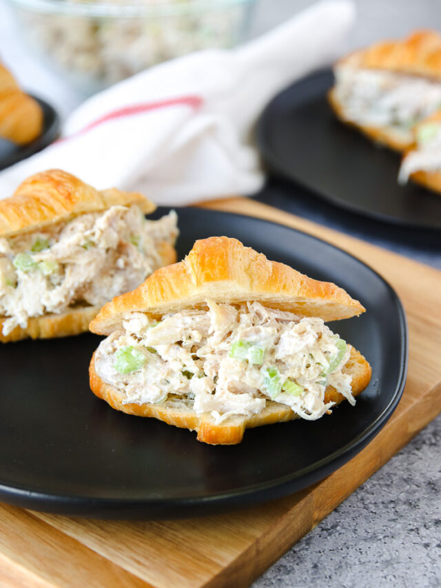 a small croissant with rotisserie chicken salad on a black plate