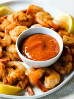 a bowl of cocktail sauce on a plate of steamed shrimp