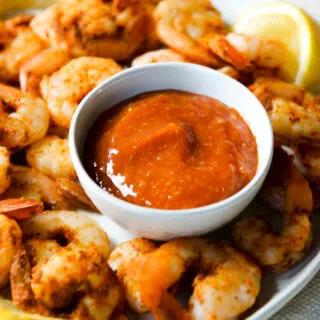 a bowl of cocktail sauce on a plate of steamed shrimp