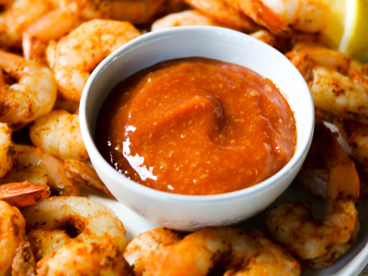 a bowl of cocktail sauce on a plate of steamed shrimp