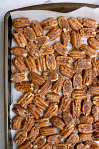 candied pecan halves on parchment paper on a cookie sheet