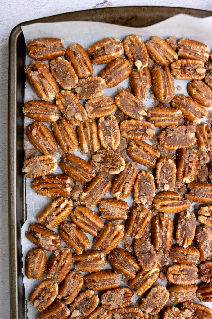 candied pecan halves on parchment paper on a cookie sheet