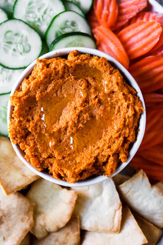 a bowl of roasted carrot hummus with olive oil drizzled on top