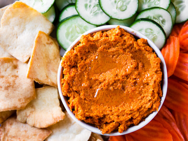 an overhead shot of roasted carrot hummus with veggies and pita chips on a plate