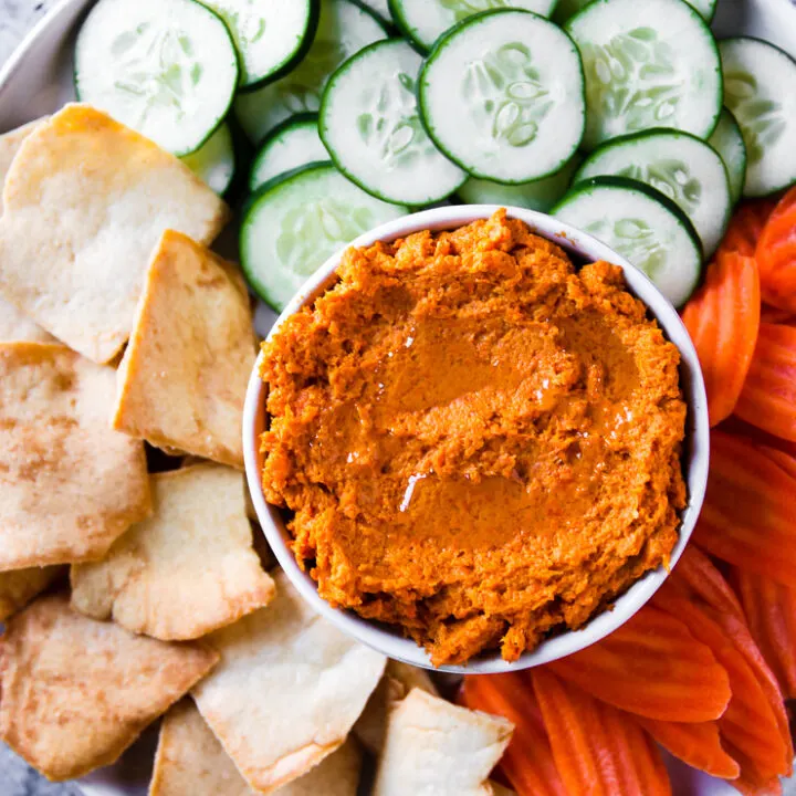 an overhead shot of roasted carrot hummus with veggies and pita chips on a plate