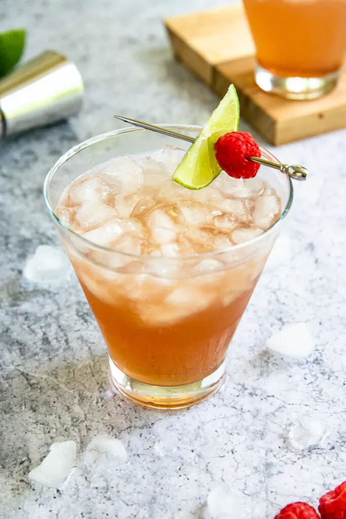 a pink chambord margarita filled with crushed ice and a metal pick with a lime slice and raspberry placed on top