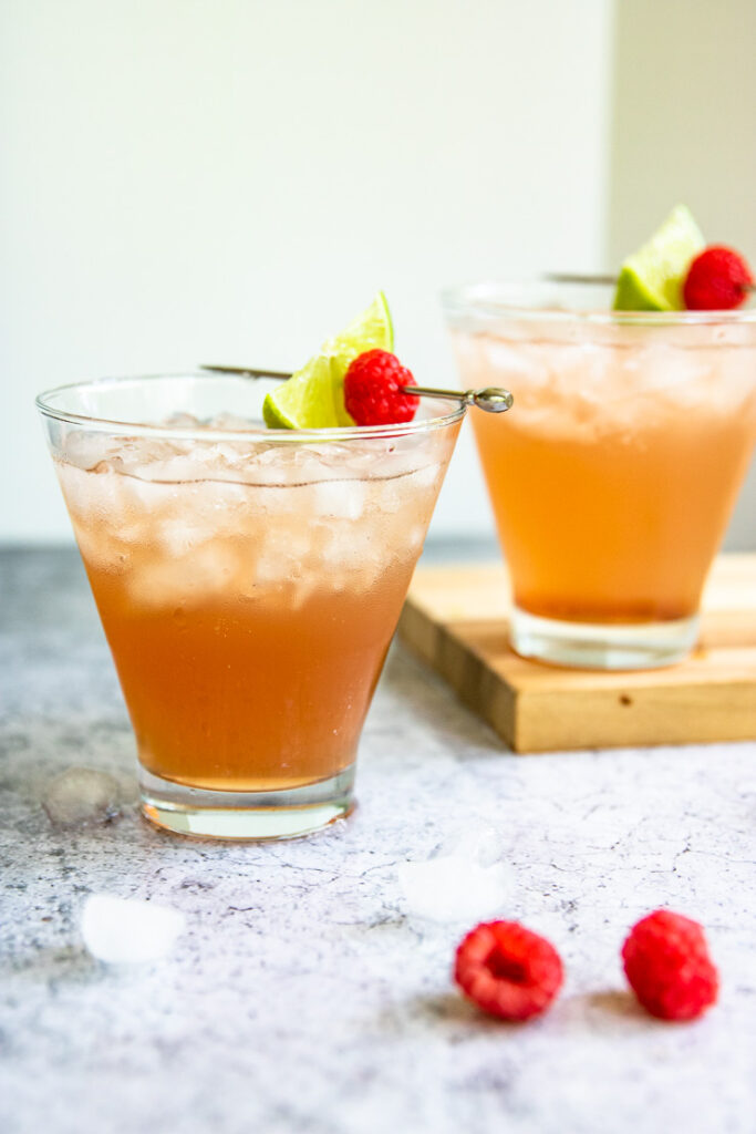 two margarita glasses with chambord margaritas and picks with lime slices and raspberries