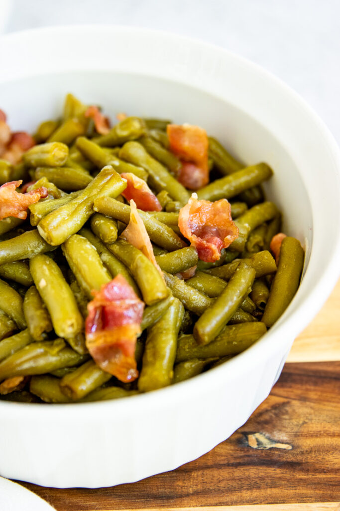 a round white baking dish with green bean and bacon casserole