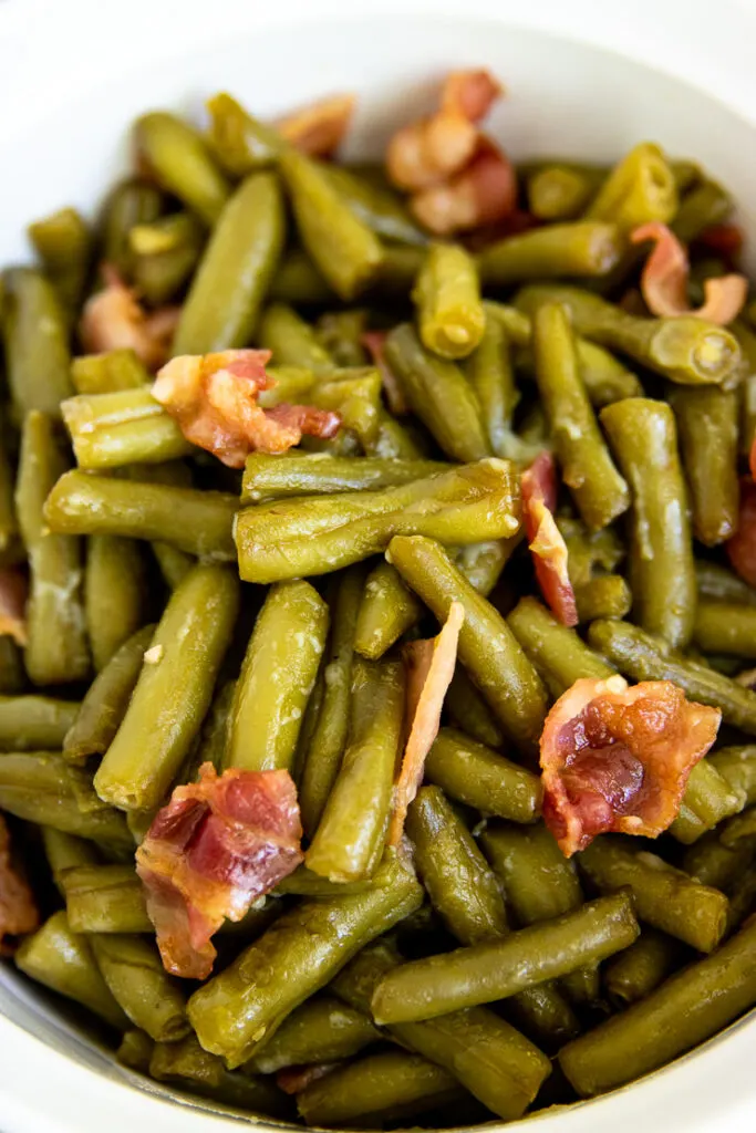 a close up of green beans and crispy bacon crumbles