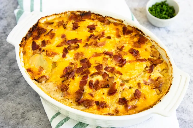 a white gratin dish with baked loaded scalloped potatoes