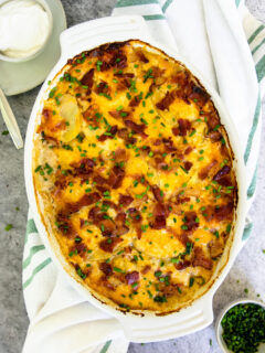 a gratin dish of loaded scalloped potatoes with diced chives on top