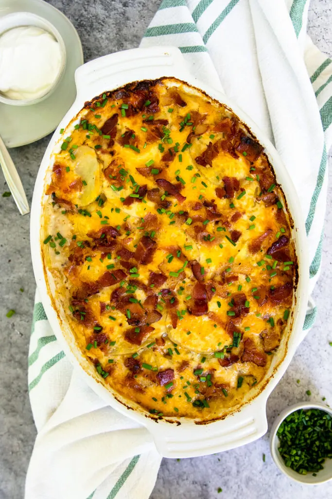 a gratin dish of loaded scalloped potatoes with diced chives on top