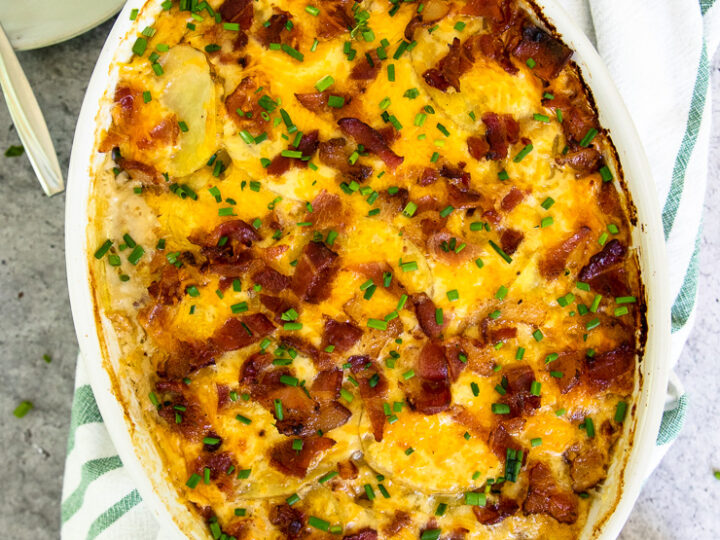 a gratin dish of loaded scalloped potatoes with diced chives on top