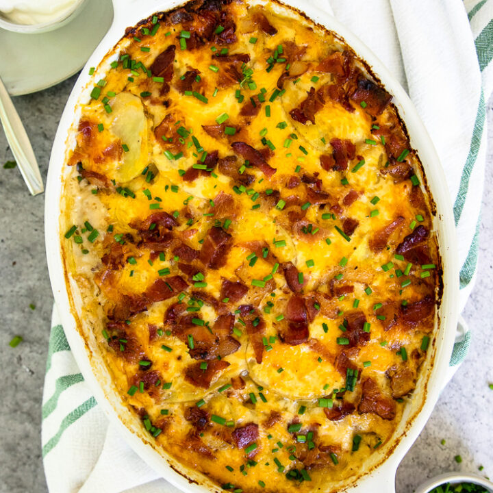 a gratin dish of loaded scalloped potatoes with diced chives on top