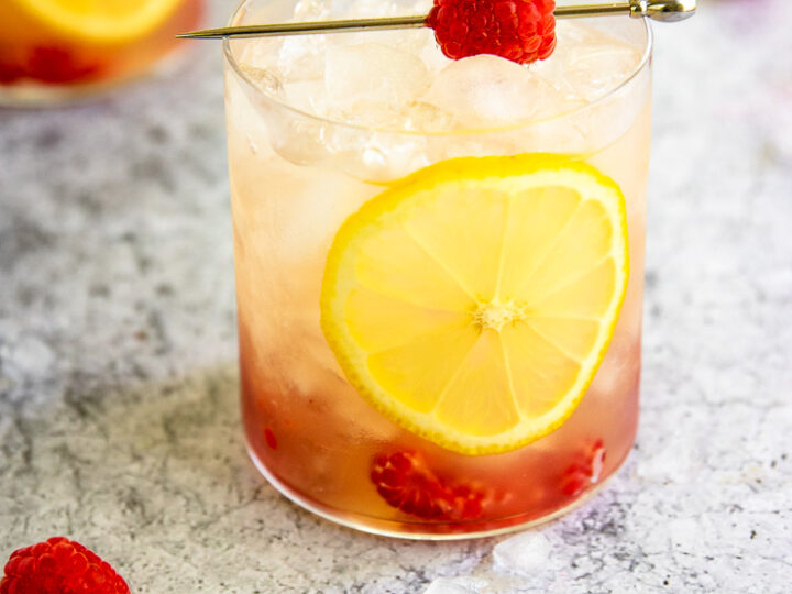 a raspberry bramble surrounded by crushed ice, raspberries, and lemon slices