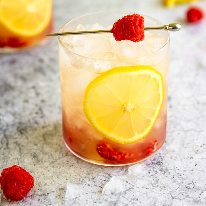 a raspberry bramble surrounded by crushed ice, raspberries, and lemon slices