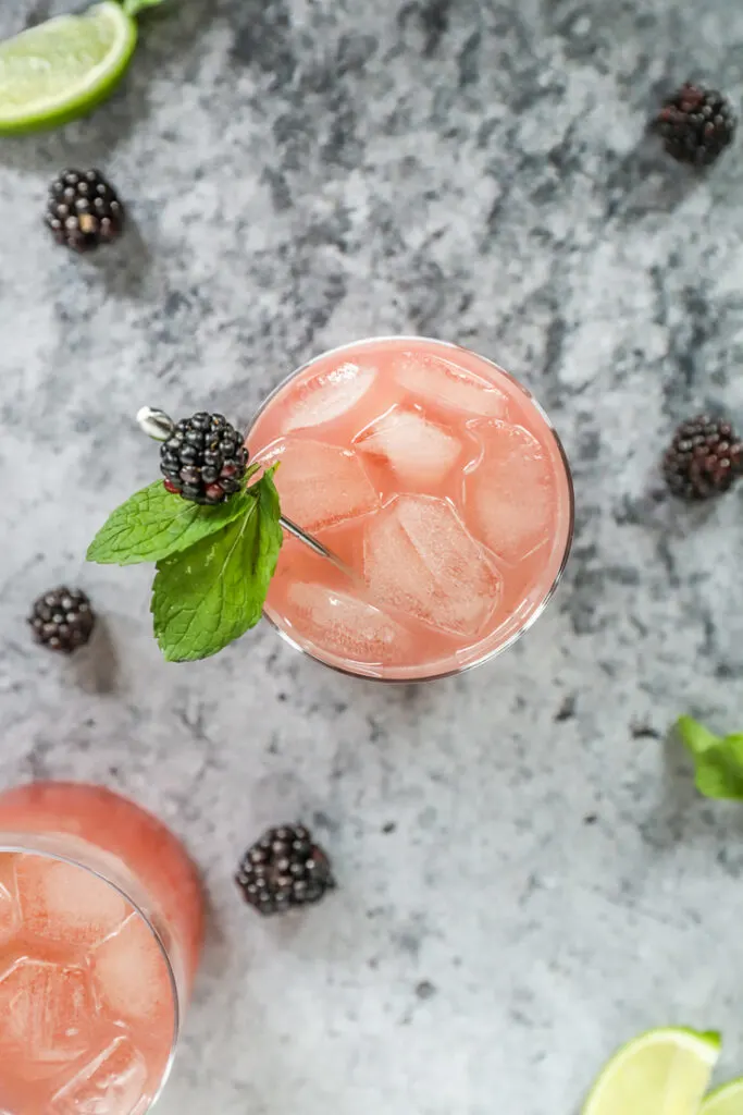 an overhead shot of a blackberry bourbon smash with blackberries scattered around