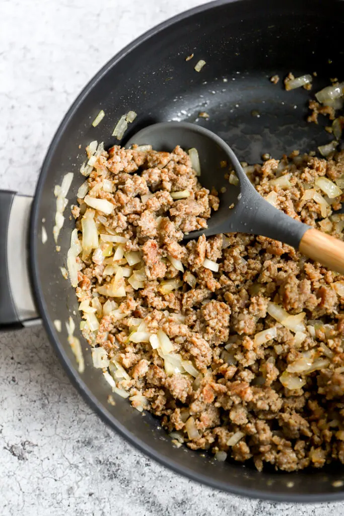 a soup pot with cooked ground sausage and cooked diced onion