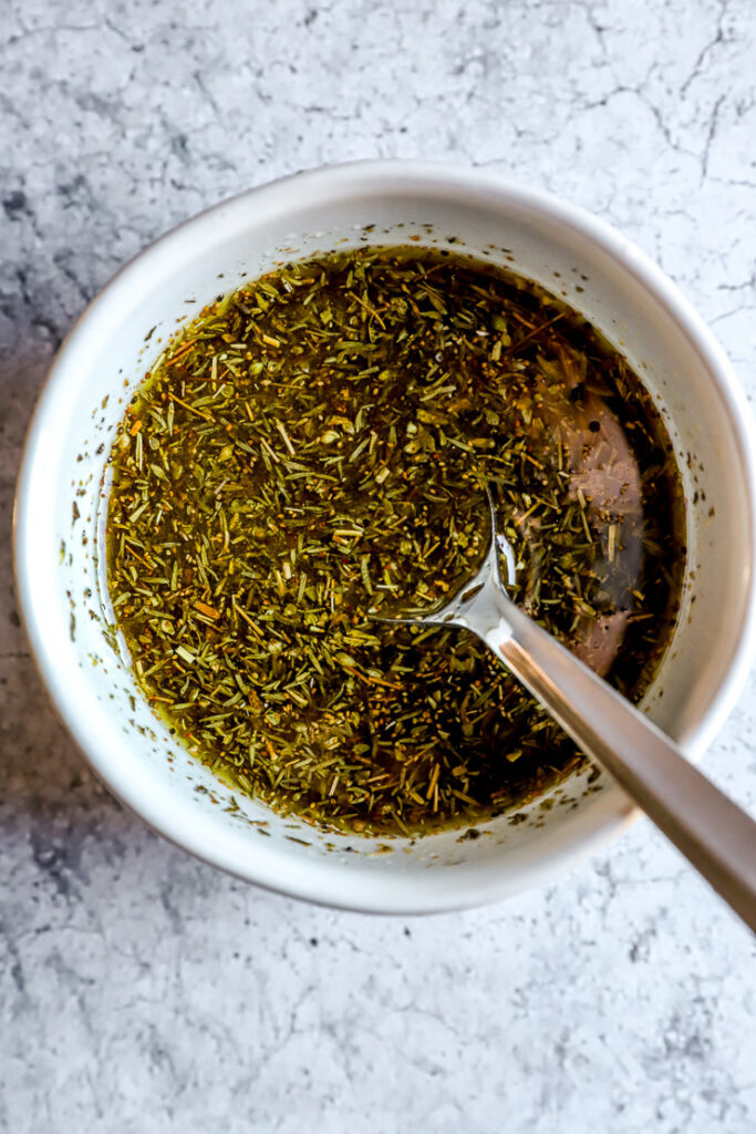 a small bowl of olive oil, lemon juice, and herbs