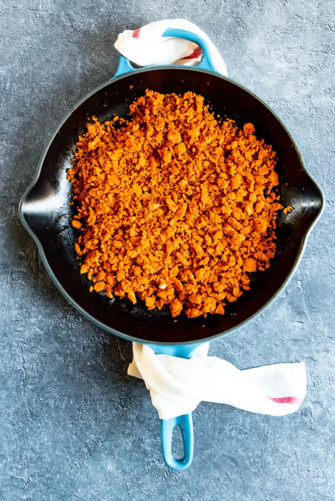 a blue cast iron enameled pan with cooked crumbled chorizo