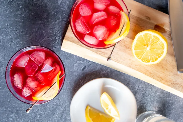 an overhead shot of two glasses of the cranberry bourbon cocktail surrounded by lemon slices