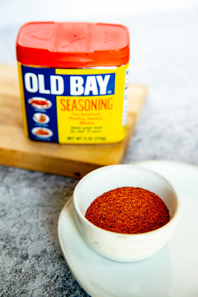 a container of old bay behind some poured into a small bowl