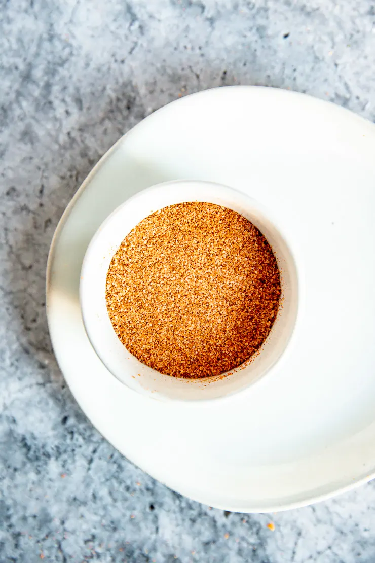 an overhead shot of a small bowl of red speckled creole seasoning