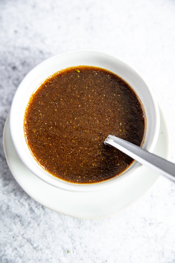 a white bowl and spoon on a white plate with balsamic vinaigrette in it