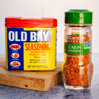 a container of old bay seasoning next to a container of cajun seasoning