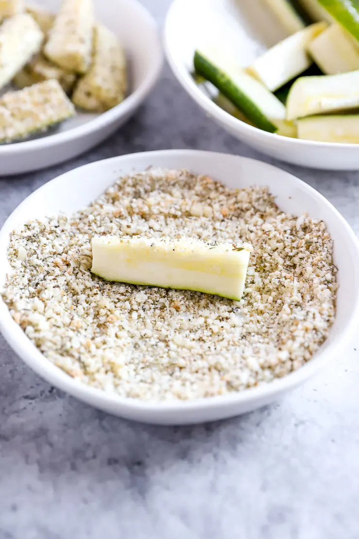 a zucchini fry being tossed in the parmeson topping mixture