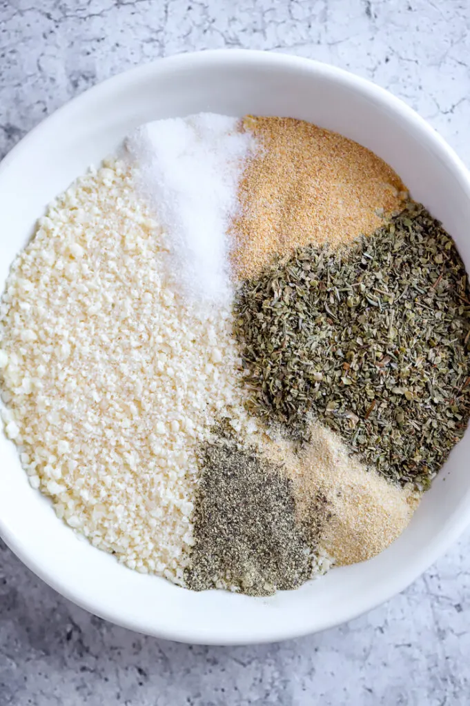 a small white bowl with parmesan, salt, pepper, garlic & onion powders, and italian seasoning