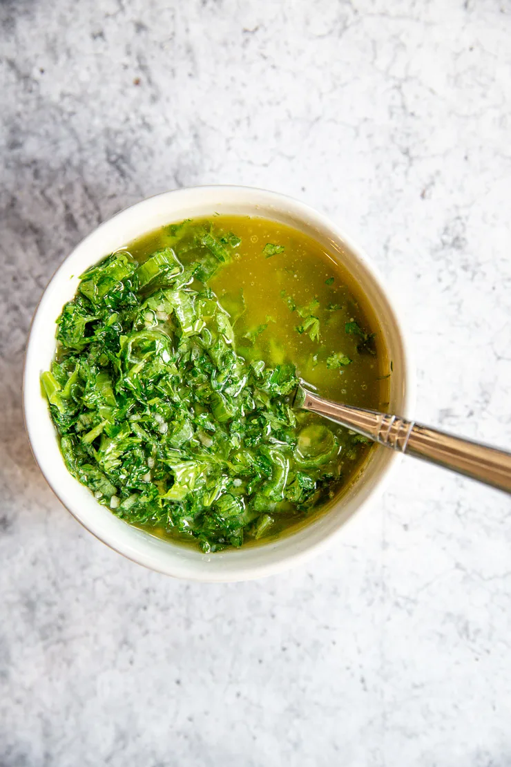 a small white bowl with herbs and melted butter