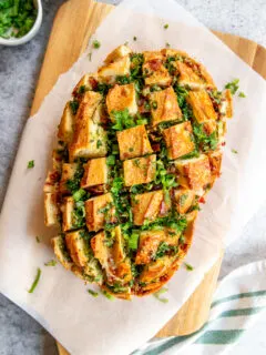 a loaf of pull apart garlic bread on parchment paper on a cutting board