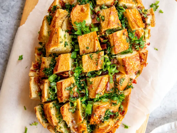 a loaf of pull apart garlic bread on parchment paper on a cutting board